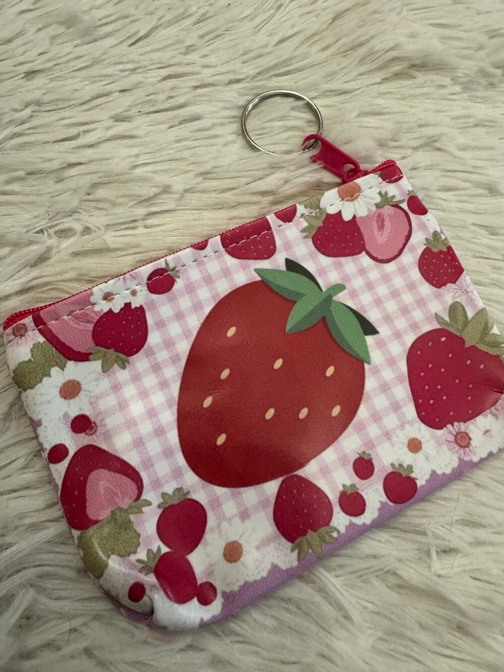 Strawberry keychain pouch with red strawberries on a white and pink background